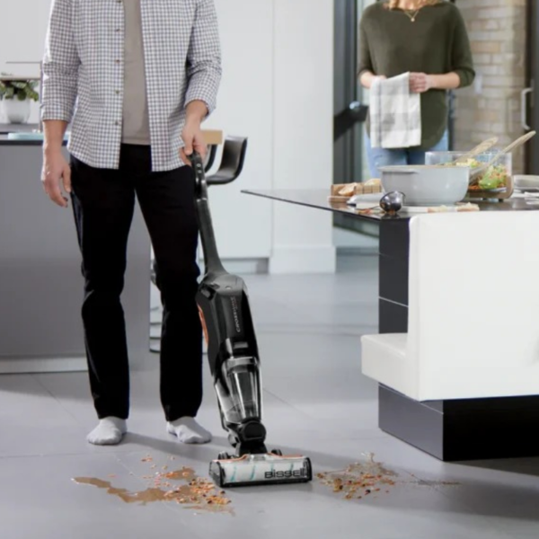 کاربر در حال استفاده از جارو شارژی بیسل مدل Cordless Max 2767Z برای تمیز کردن کف خانه
